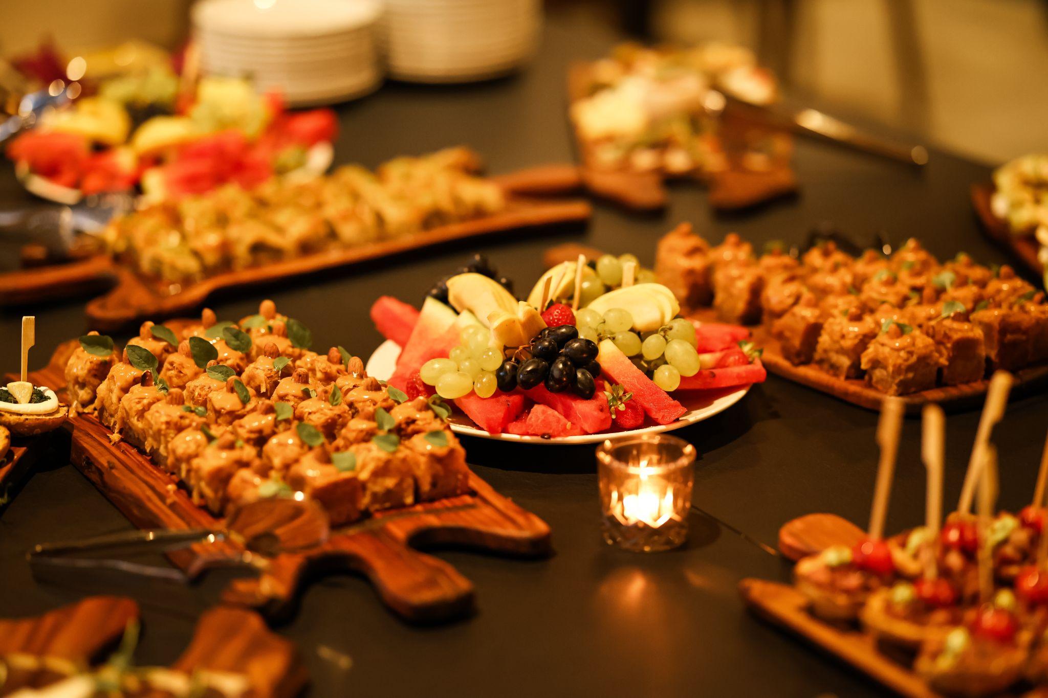 A platter of fruits and other desserts with a candle on the table