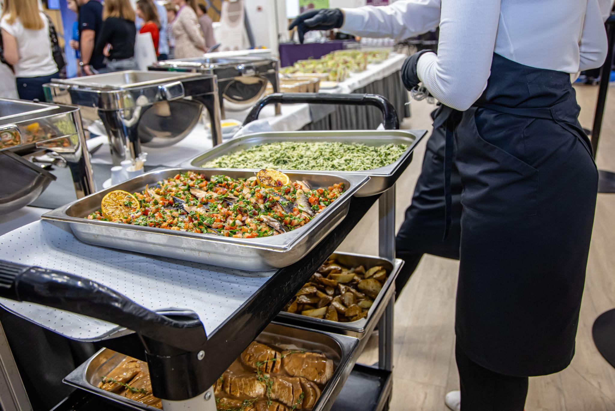 Food cart with trays of hot dishes at a corporate catering event.